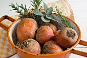 Golden beets in a colander with rosemary and sage