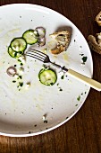 The remains of courgette carpaccio and bread on a plate with a fork