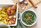 Bacon-wrapped pears with roast potatoes and a bean and onion salad
