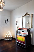 Retro Musikbox unter Spiegel mit antikem Goldrahmen, moderne Kunst und ausgefallene Leuchtobjekte im Wohnraum