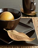 Place setting with brown square plates and dry leaf resting on plate