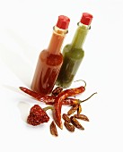 Bottles of red and green chilli sauce and various dried chilli peppers