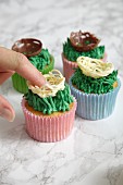 Easter cupcakes being decorated with Easter chocolate nests