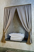 Niche with draped curtains in bathroom wall patinated with raw umber
