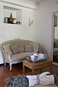 Old, stripped side table and antique couch next to full-length mirror; bunch of lavender in foreground