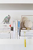 Books and ornaments on white wall-mounted shelf