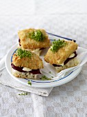 White bread topped with breaded fish fillet, beetroot and cress