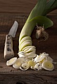 An arrangement of leek and an old vegetable knife on a rustic wooden table