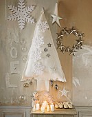 Weihnachtsdeko: Kerzen, Christbaum aus weißem Stoff, Sterne und Kinderschuhe