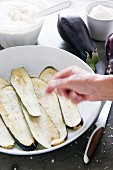 Aubergine slices being sprinkled with salt