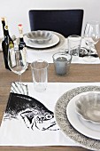 Gedecke in Weiß und Grau auf Tischset mit Fischmotiv