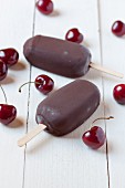 Chocolate-covered banana and cherry ice cream sticks and fresh cherries