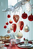 Hearts and Christmas tree baubles in red and white hanging on a branch over a breakfast table