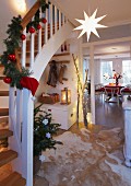A hallway decorated for Christmas with a decorated banister and a view into the dining room