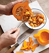 Hokkaido pumpkin being deseeded with a dessert spoon