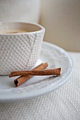 A cup of eggnog with cinnamon sticks