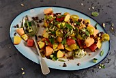 A colourful melon salad with tomatoes and pesto
