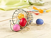 Colourful Easter eggs in a wire basket with straw