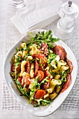 A pasta salad with tomatoes, salami and rocket (seen from above)