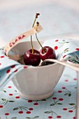 Cherries on a silver spoon in a bowl lined with a napkin