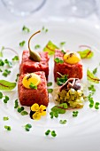 Beef tartare with caper fruits and egg yolks served with a gherkin and anchovy salad
