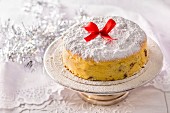 A Polish Christmas cheesecake decorated with a red bow on a silver cake stand