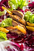 A colourful salad with duck breast, orange fillets and pomegranate seeds