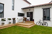 Modern house with rustic wooden terrace, lawn and bicycle