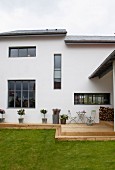 Modern house with rustic wooden terrace and green lawn