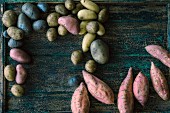 Various types of potatoes and sweet potatoes on a wooden surface