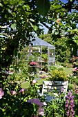 Secluded seating area in flowering garden with greenhouse