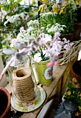 Garnspule mit Glashaube und Gartenblumen auf Holzbank
