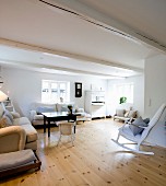 White rocking chair in lounge area with sofas and black table on wooden floor