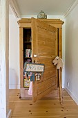 Pale wooden farmhouse cupboard with open door, sign hanging from doorknob and hobby horse to one side