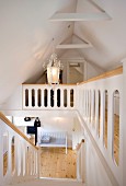Treppenhaus mit Galerie unter ausgebautem Dachraum, weiss lackierte Holztreppe und Holz Handlauf