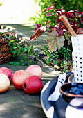 Rote Äpfel und teilweise sichtbares Geschirr auf rustikalem Tisch im Freien