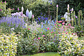 Blühender Garten mit blauer Veronica, Fingerhut und Lerchensporn, dazwischen Gartendeko