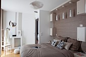 Pendant lamp above double bed against wall with wood-grain effect