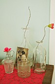 Poppies in various bottles and nostalgic photo on pink lace cloth