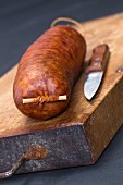 Saucisse De Morteau (French sausage) on a chopping board with a knife