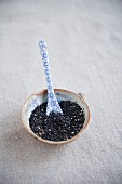 Black sesame seeds in a bowl with a spoon