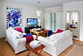 Weiß möbliertes Wohnzimmer mit starken Farbakzenten in Magenta und Königsblau