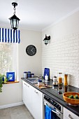 Modern kitchen counter with splashback tiled with white, structured strip tiles and accents of colour provided by blue accessories