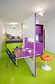 Modular kitchen with integrated dining table and bed on platform with storage space in colourful mini-apartment