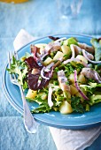 A mixed leaf salad with soused herring and potatoes