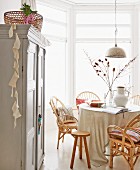 Dining room with wicker chairs, Oriental, silver pendant lamp and country-house cupboard in foreground