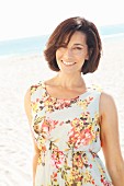 Brunette woman wearing floral summer dress on beach