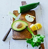 Ingredients for green smoothies: avocado, celery, lemon zest, apple and cucumber on a chopping board