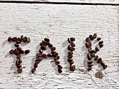 The word FAIR spelt out in coffee beans on white floor boards