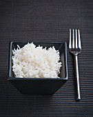 Gekochter Reis in schwarzem Schälchen auf schwarzem Untergrund